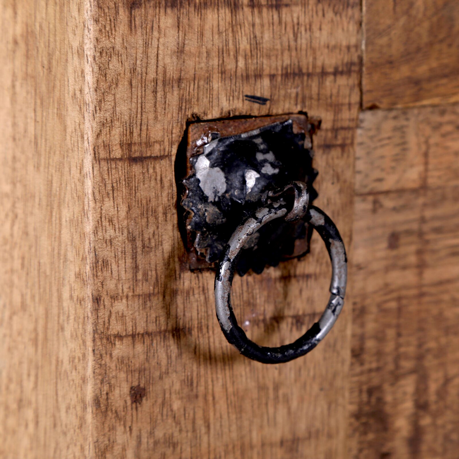 Close-up van een rustiek houten secretaire met een antieke metalen ringgreep, gezien vanaf de zijkant.