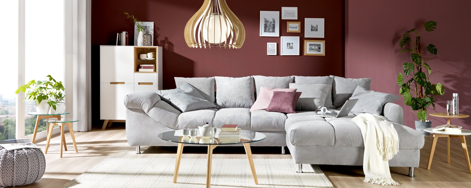 Gezellige grijze hoekbank (L) in een moderne woonkamer, gezien van voren, met sierkussens en een elegante salontafel.