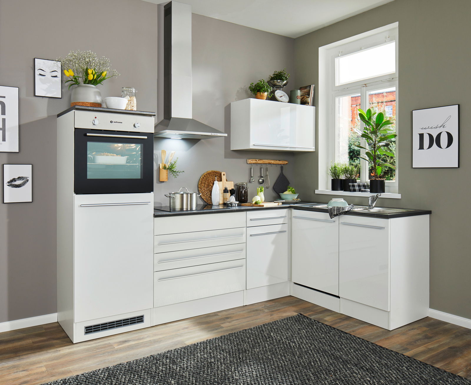 Moderne weiße Küche mit Eckunterschrank, Backofen, Dunstabzugshaube und Spüle, aus der Perspektive von vorne links.