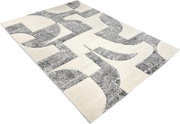 Moderner Teppich in Creme mit grauem, abstrakt-geometrischem Muster, schräg von oben in Perspektive fotografiert