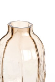 Close-up in vooraanzicht van een transparante vaas van amberkleurig glas met organische golvende vorm en onregelmatige rand.