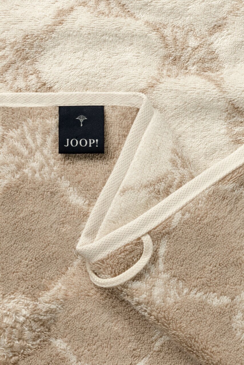 JOOP! Gästetuch Nahaufnahme eines beigen Gästetuchs mit geometrischem Muster und einem schwarzen Etikett mit der Aufschrift 'JOOP!'
