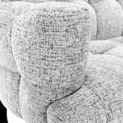 Detailopname vanuit schuin vooraanzicht van een lichtgrijze gemêleerde stoffen fauteuil met zacht afgeronde armleuning en royale zitting