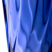 Nahaufnahme eines blauen Trinkglases mit gedrehtem Design, seitliche Perspektive