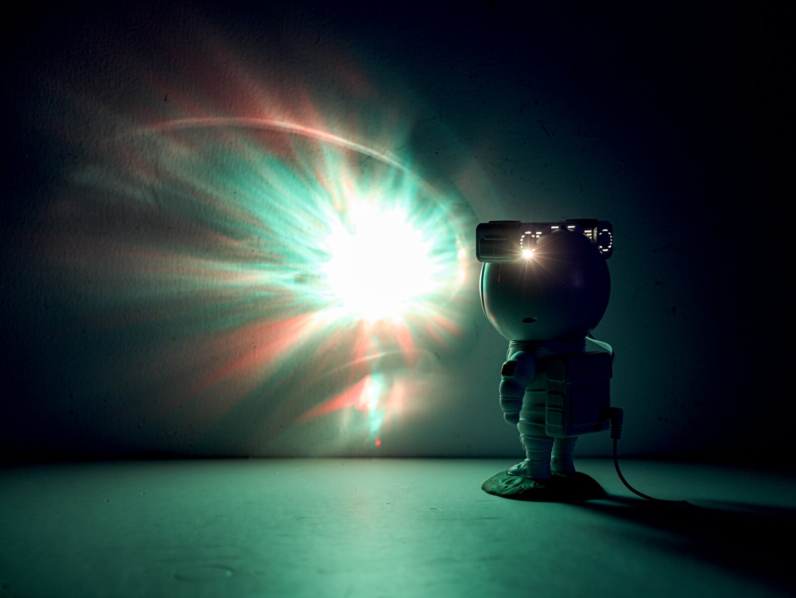 Astronautenfigur mit LED-Lichtprojektion an der Wand, seitliche Perspektive