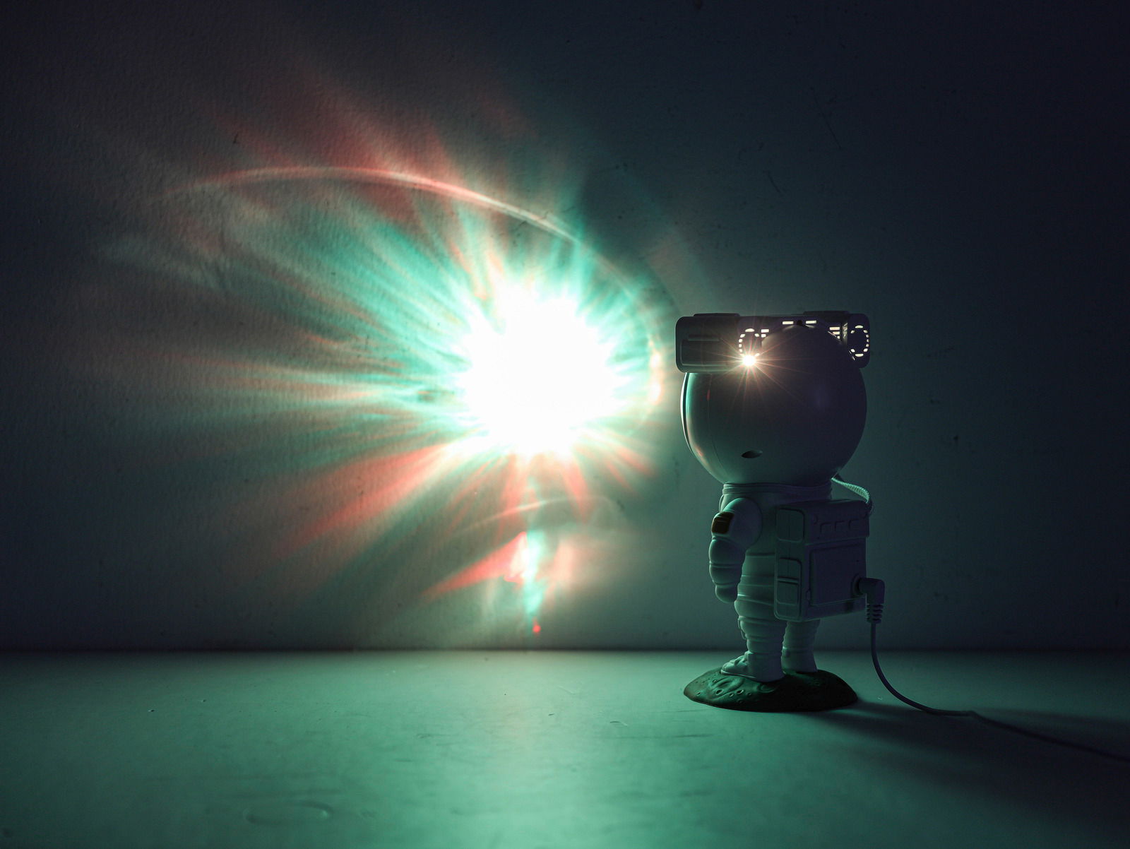 Astronautenfigur mit LED-Lichtprojektion an der Wand, seitliche Perspektive