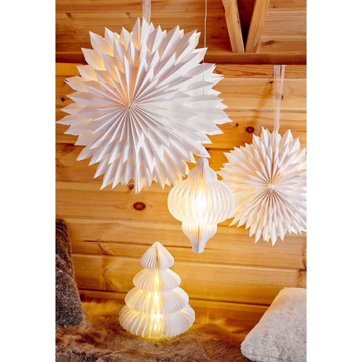 Een boom van papier met micro-leds en hangende papieren lantaarns in een gezellige kamer met houten lambrisering, zijaanzicht