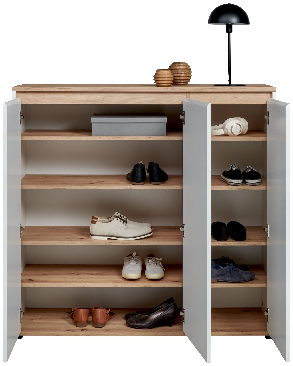 XL-Schuhschrank mit offenen Türen, gefüllt mit verschiedenen Schuhen, aus der Frontalperspektive fotografiert. Obenauf stehen eine Lampe und Dekorationsgegenstände.