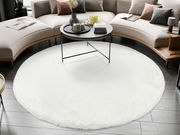 Runder weißer Fellteppich in einem modernen Wohnzimmer, umgeben von einem geschwungenen Sofa und einem runden Couchtisch, aus der Vogelperspektive betrachtet.