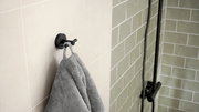 Schwarzer Bademantelhaken von tesa MOON BLACK an einer Badezimmerwand, seitliche Perspektive