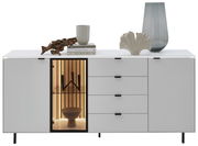 Modernes weißes Sideboard mit vier Schubladen und zwei Türen, eine davon mit Glas und Beleuchtung. Dekoriert mit Büchern, einer Tasse, einer Vase und einer Skulptur. Frontale Perspektive.