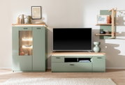 Frontale Ansicht einer modernen Wohnwand in Salbeigrün mit Holzabsetzungen: Vitrine mit LED-Beleuchtung, TV-Lowboard mit Flachbildfernseher und Wandregal mit Deko in einem hellen Wohnzimmer.