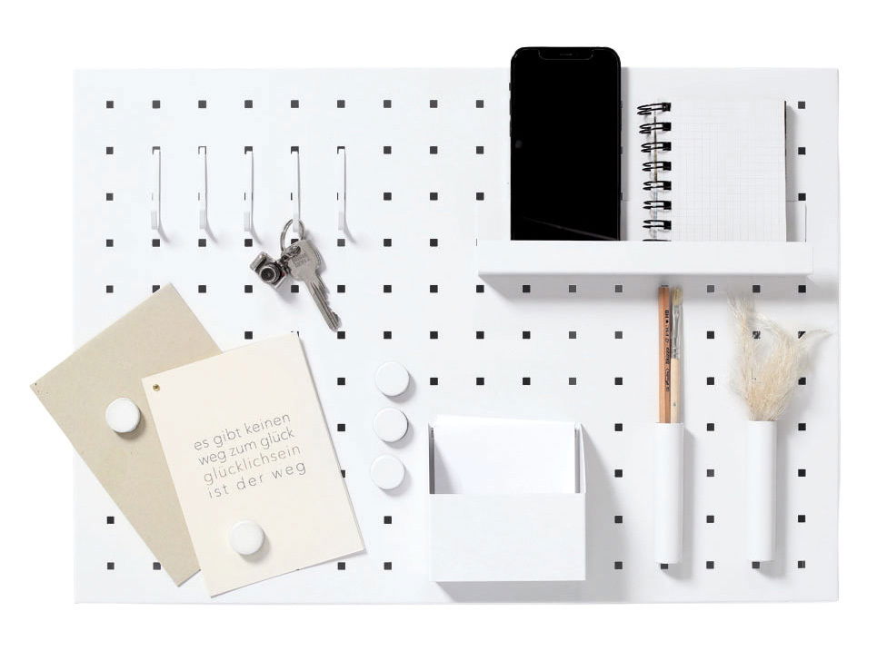 Memoboard mit Utensilien, frontal abgebildet, mit Haken, Schlüssel, Notizbuch, Stift und Dekoration.