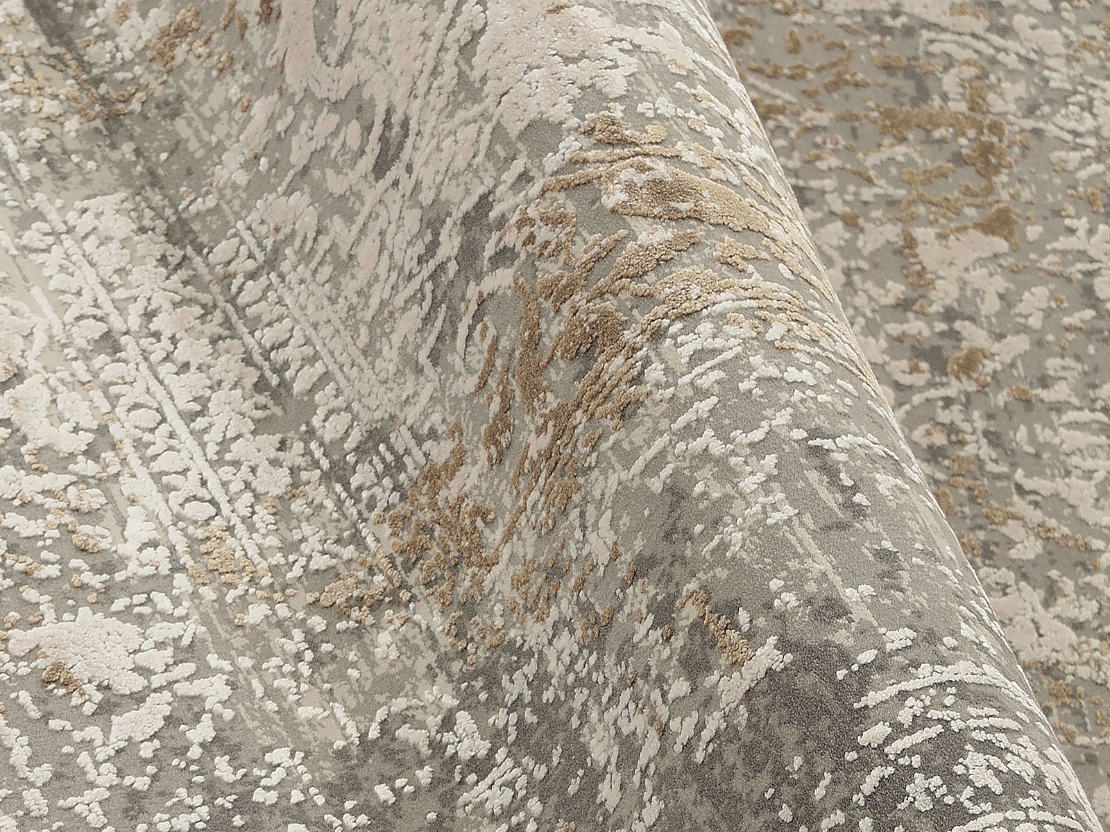 Nahaufnahme eines Designer-Teppichs mit abstraktem Muster in Grau- und Beigetönen, perspektivisch von der Seite aufgenommen.