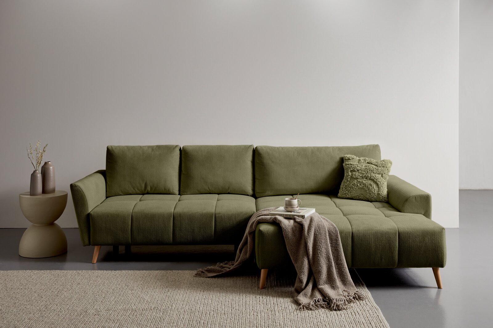 Z2 Ecksofa ZELDA Olivgrünes Sofa mit rechter Recamiere/Chaiselongue und Holzfüßen in minimalistischer Wohnszene, Frontansicht auf Augenhöhe.