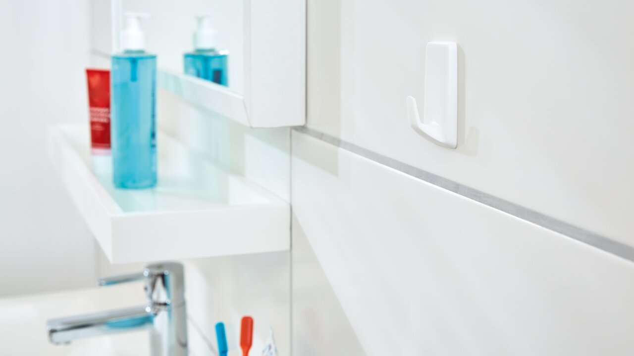 Close-up van een witte tesa Powerstrips-haak aan een badkamermuur, met een modern, minimalistisch ontwerp.