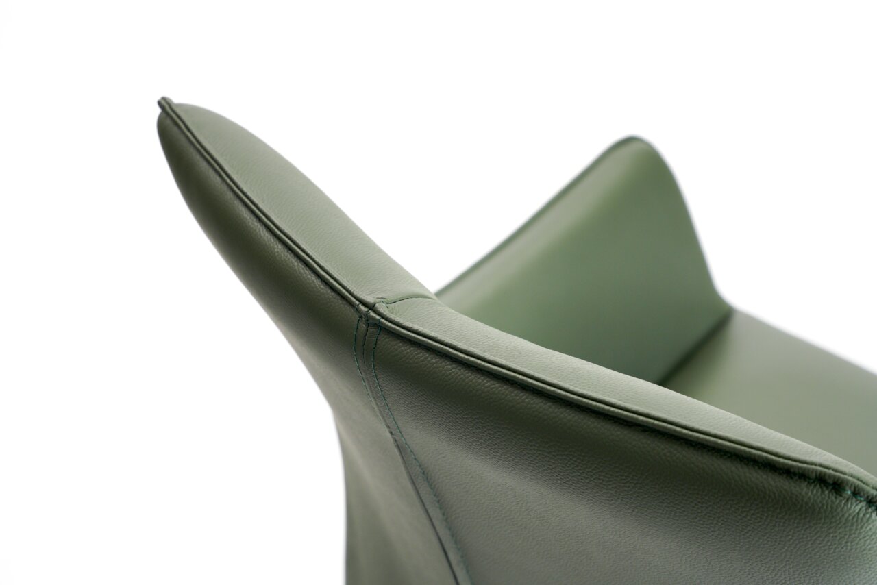 Nahaufnahme eines grünen Armlehnstuhls aus Leder, seitliche Perspektive