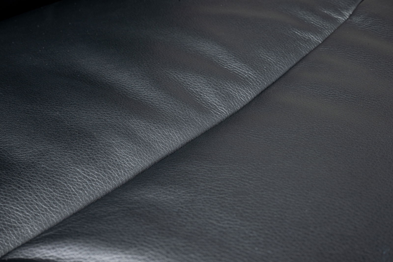 Nahaufnahme der schwarzen Lederoberfläche eines Chefsessels, von oben betrachtet.