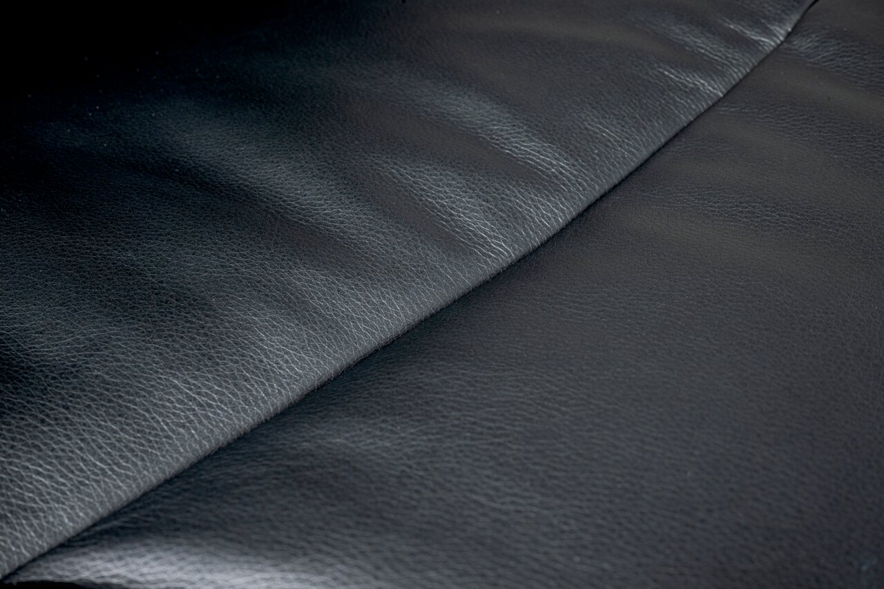 Nahaufnahme der schwarzen Lederoberfläche eines Chefsessels, von oben betrachtet.
