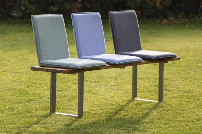 Drei farbige Sitzschalen auf einer Bank im Freien, seitliche Perspektive