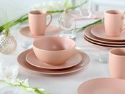 Pastellrosa Geschirr-Set mit Schüssel auf Teller und Tassen auf gedecktem Tisch, fotografiert aus leicht erhöhter, schräger Frontperspektive