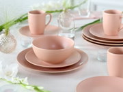 Pastellrosa Geschirr-Set mit Schüssel auf Teller und Tassen auf gedecktem Tisch, fotografiert aus leicht erhöhter, schräger Frontperspektive