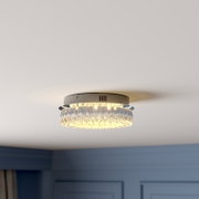 Runde, bündig montierte Deckenleuchte mit klaren Kristallglas-Elementen und warmweißem Licht, fotografiert aus leicht schräger Untersicht an der Zimmerdecke