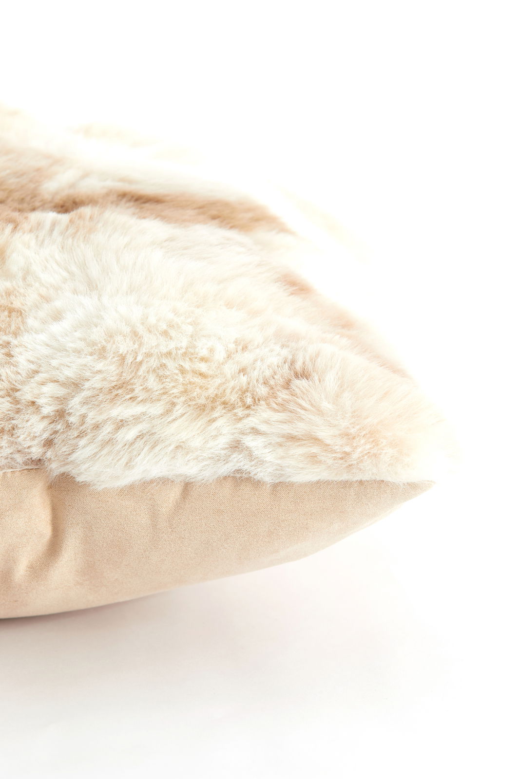 Nahaufnahme eines weichen, flauschigen Kissens mit beiger und cremefarbener Textur, seitliche Perspektive.