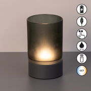 Akku-Windlicht mit zylindrischem, mattem Glas und dunklem Sockel, frontal fotografiert. Symbole für USB-Ladung, Touch-Bedienung, IP54-Schutz, Fernbedienung und CCT-Farbtemperaturregelung sind sichtbar.