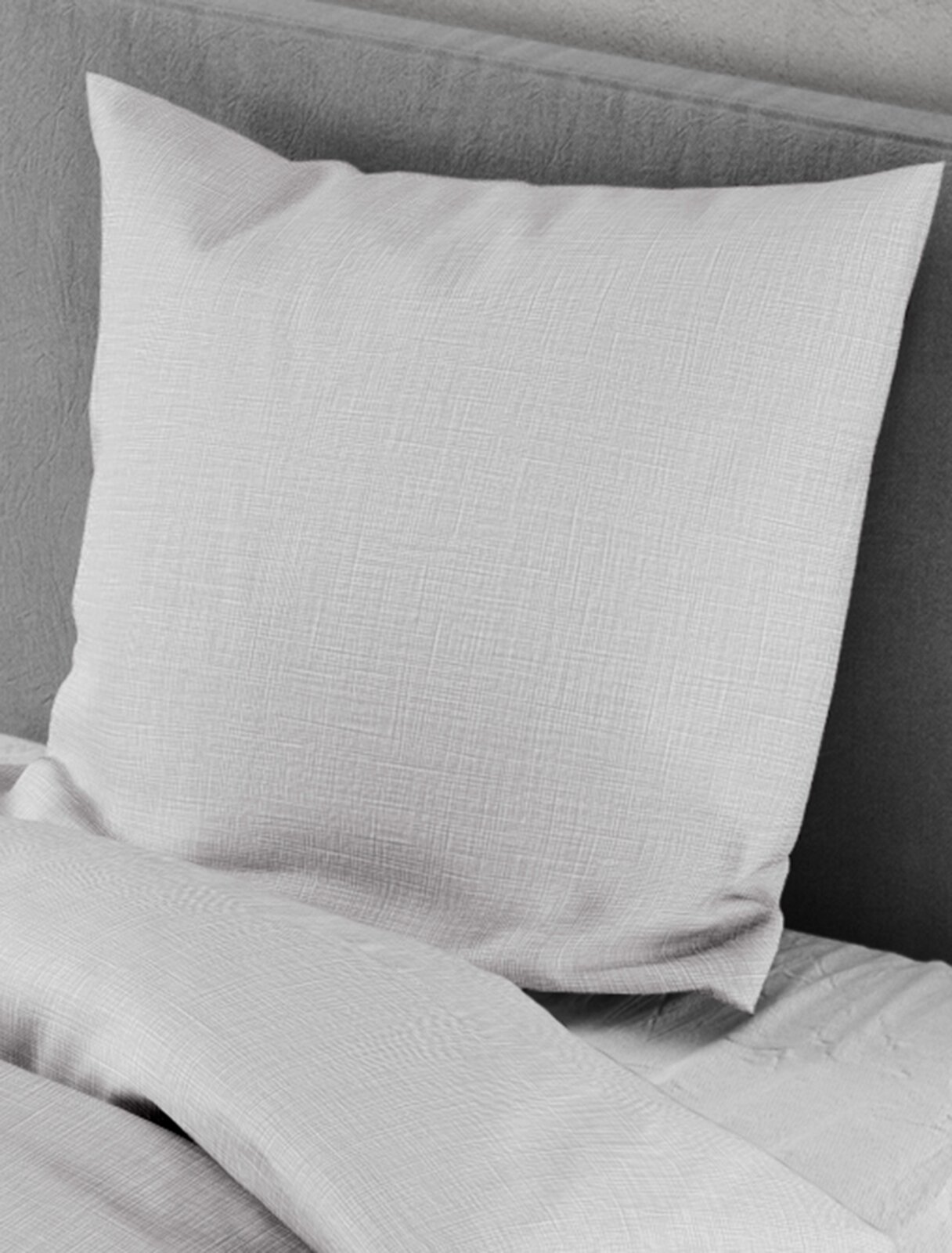 Bettwäsche-Set in hellem Grau mit feiner Struktur, bestehend aus einem Kissenbezug und einem Bettdeckenbezug, auf einem Bett arrangiert, seitliche Perspektive.