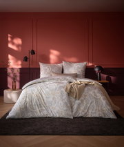 Bettwäsche-Set in einem stilvollen Schlafzimmer mit roter Wand, bestehend aus einem Bettbezug und Kissenbezügen mit Paisley-Muster, aus der Perspektive von vorne aufgenommen.