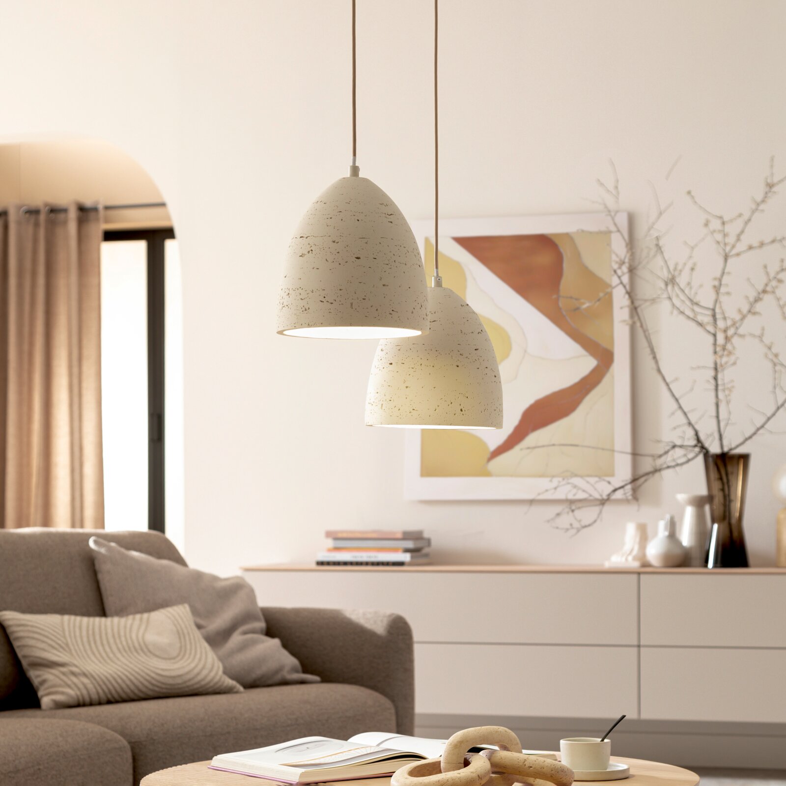 Zwei cremefarbene, gesprenkelte Pendelleuchten in eiförmiger Form hängen im Wohnzimmer über dem Wohnbereich; Perspektive: leicht von unten, frontale Ansicht.
