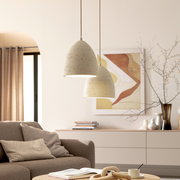 Zwei cremefarbene, gesprenkelte Pendelleuchten in eiförmiger Form hängen im Wohnzimmer über dem Wohnbereich; Perspektive: leicht von unten, frontale Ansicht.