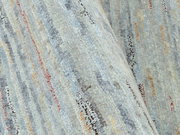 Nahaufnahme eines Wollteppichs mit bunten Streifen in verschiedenen Farben, aus seitlicher Perspektive aufgenommen.