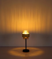 Moderne Tischlampe mit schwarzem Ständer, rundem Fuß und geriffeltem Glas-Schirm mit warmem Licht, frontal aus leicht erhöhter Perspektive fotografiert