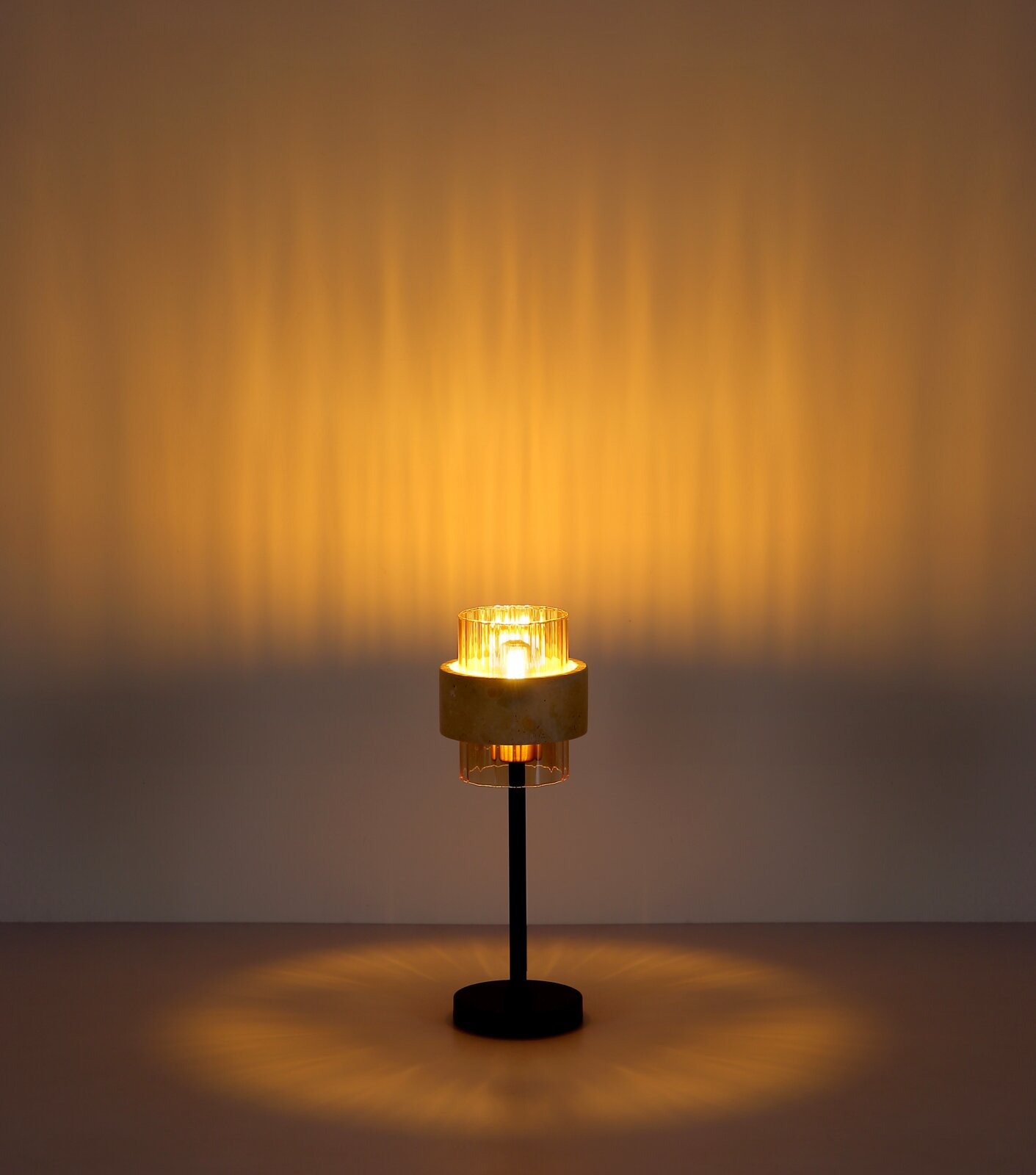 Moderne Tischlampe mit schwarzem Ständer, rundem Fuß und geriffeltem Glas-Schirm mit warmem Licht, frontal aus leicht erhöhter Perspektive fotografiert