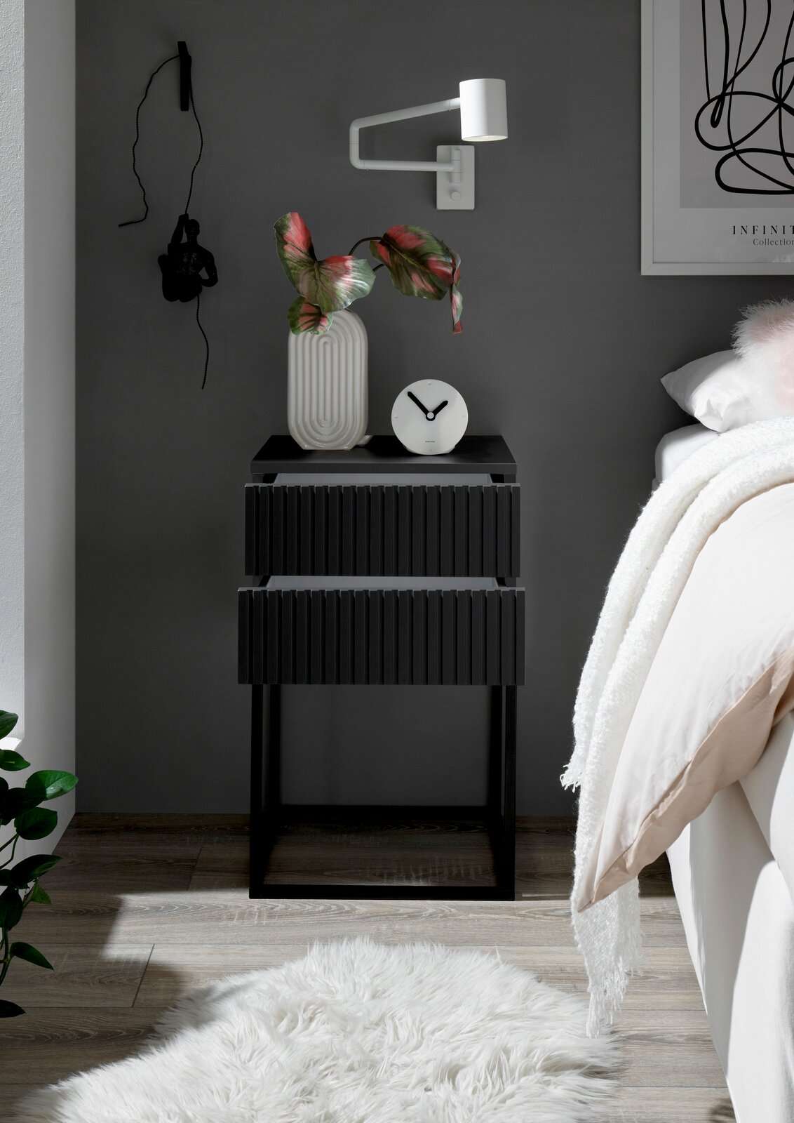 Moderne schwarze Nachtkommode mit zwei Schubladen, dekoriert mit einer Vase und einer Uhr, seitliche Perspektive.