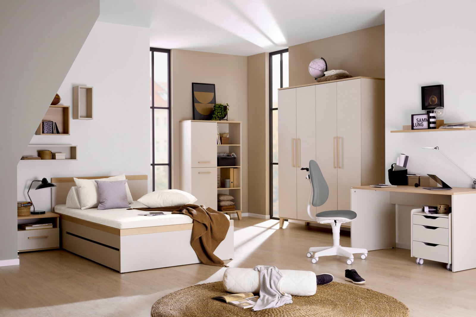 Helles, modern eingerichtetes Jugendzimmer mit Bett, Kleiderschrank, Regalen und Schreibtisch in Weiß und Holzoptik, aus einer frontalen Weitwinkelperspektive betrachtet.