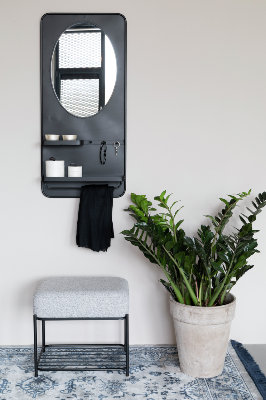 Z2 Hocker MILOU Moderner Hocker mit grauem Polster und schwarzem Metallgestell, frontal fotografiert, neben einem großen grünen Pflanzenkübel auf einem gemusterten Teppich.