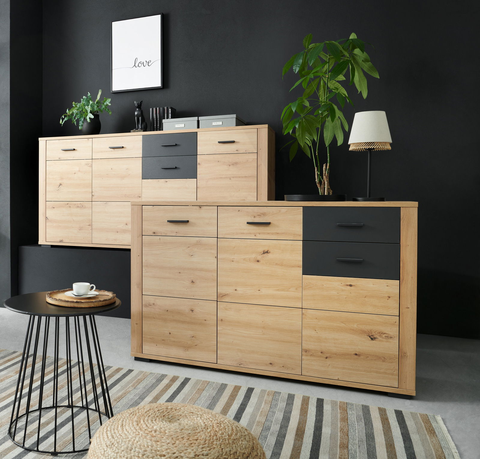 Modernes Sideboard aus Holz mit schwarzen Schubladen, dekoriert mit Pflanzen und einer Lampe, in einer stilvollen Wohnzimmerecke. Perspektive von vorne.