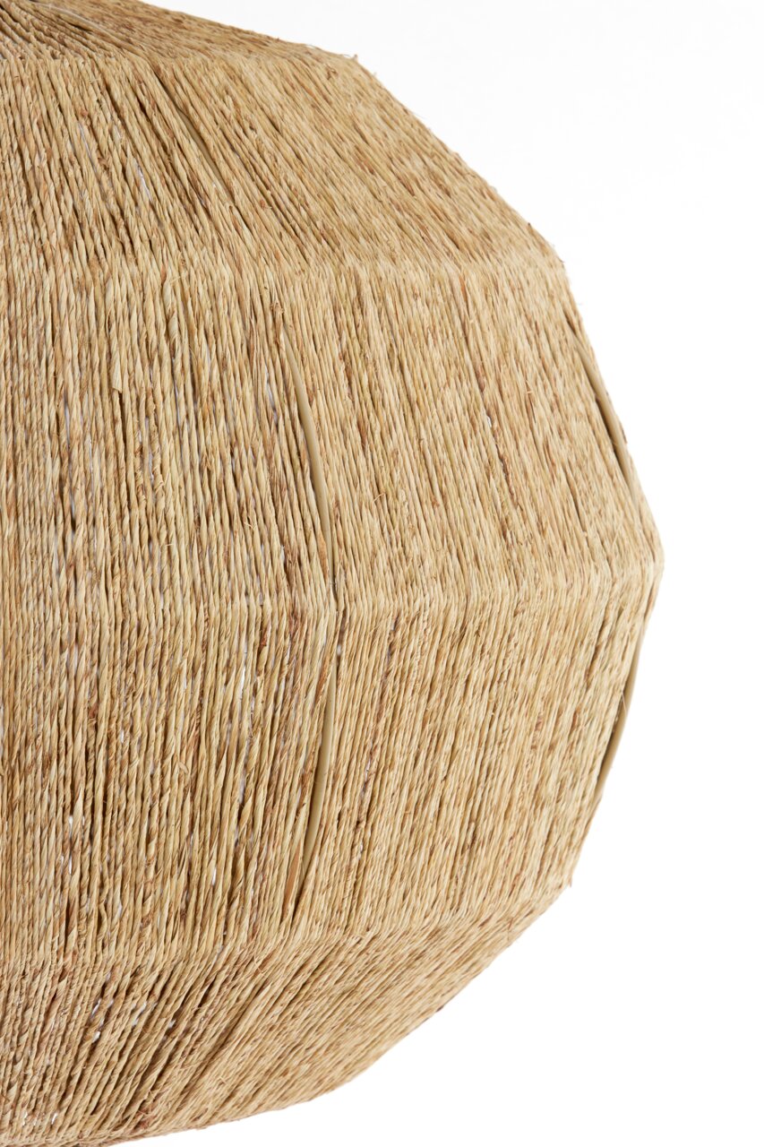 Close-up van een hanglamp met een natuurlijke, gevlochten structuur van stro of bast, gezien vanaf de zijkant.