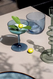 Elegante Sektschale aus blauem Glas mit dekorativer Zitrone und Blättern, von oben fotografiert.