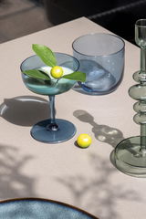 Elegante Sektschale aus blauem Glas mit dekorativer Zitrone und Blättern, von oben fotografiert.