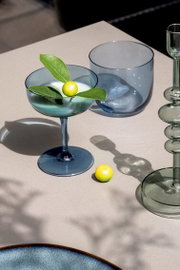 Elegante Sektschale aus blauem Glas mit dekorativer Zitrone und Blättern, von oben fotografiert.