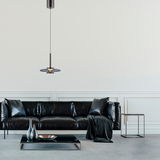 Moderne Pendelleuchte PURE Vitrum in einem eleganten Wohnzimmer, von vorne betrachtet, über einem schwarzen Ledersofa hängend.