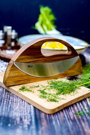 Doppel-Wiegemesser WAVE aus Holz und Edelstahl, seitliche Perspektive, auf einem Schneidebrett mit frischen Kräutern.