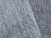 Nahaufnahme eines grauen Wollteppichs mit leichtem Faltenwurf.