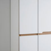 Nahaufnahme eines weißen Garderobenschranks mit Holzdetails, seitliche Perspektive