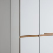 Nahaufnahme eines weißen Garderobenschranks mit Holzdetails, seitliche Perspektive