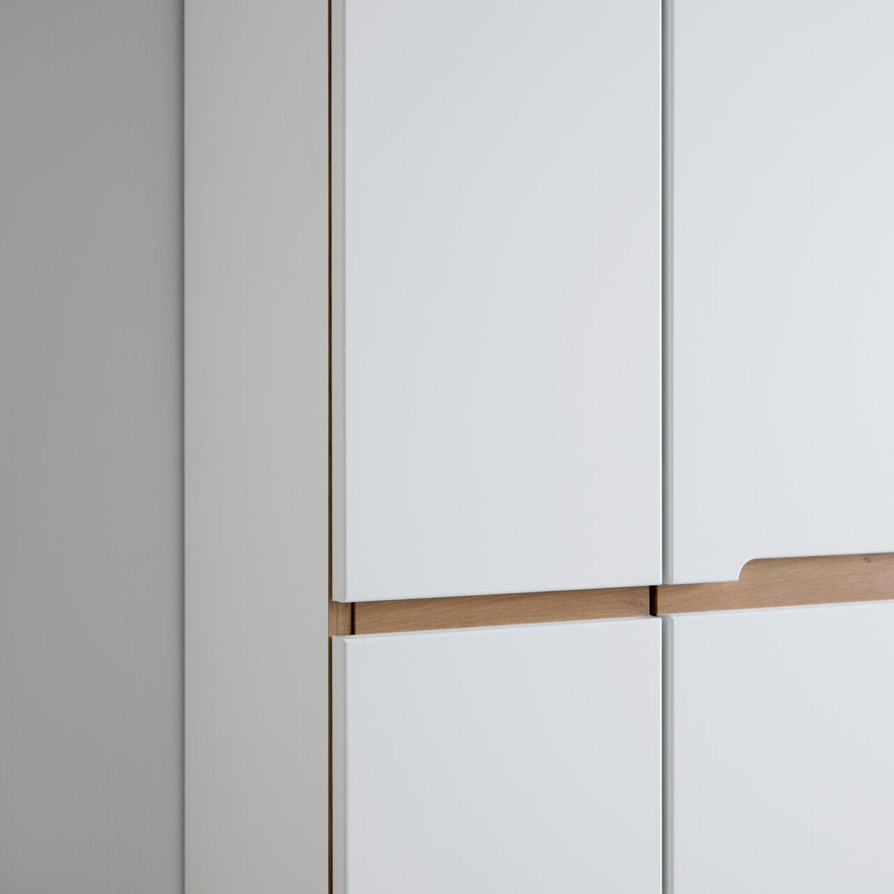 Nahaufnahme eines weißen Garderobenschranks mit Holzdetails, seitliche Perspektive